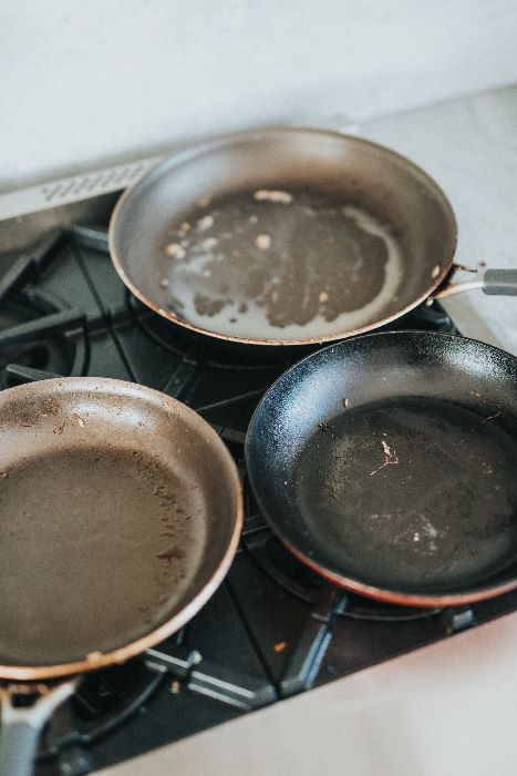 3 dirty Hard Anodized pans on stove